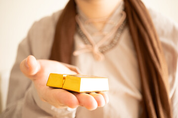 Saudi Arabian peasant in costume holds out gold bars