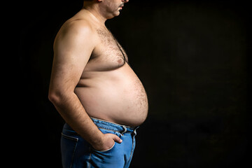 Side view of a fat black man with a large belly in dark background