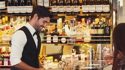 Smiling smart bartender pouring soda or tonic into glass to serve customer with friend at beverage bar counter of welcome drink with charm costume professionalism first impression greeting. Vinosity.
