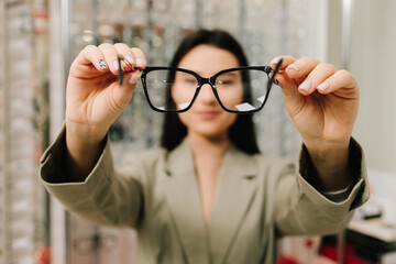 Eyesight correction. Stand of eyeglasses with different frames in the optical store. Customer...
