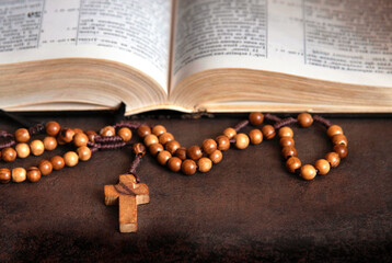 Wooden rosary and open Bible in the background