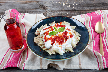 Turkish traditional food ravioli with yoghurt and tomato sauce in plate, manti