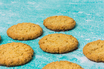 Golden-brown cookies are spread out on a blue background. Their homemade appearance evokes warmth, sweetness, and indulgence, making it perfect for dessert and baking themes.