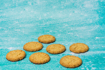 Golden-brown cookies are spread out on a blue background. Their homemade appearance evokes warmth, sweetness, and indulgence, making it perfect for dessert and baking themes.