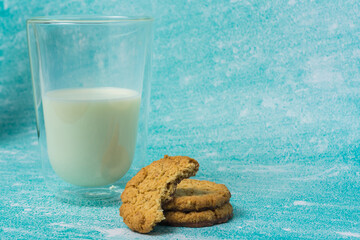 Glass of milk and a cookie on a table. The cookie is half eaten. Concept of comfort and relaxation, as it is a simple and familiar scene of enjoying a snack