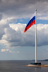 Fototapeta premium Flag of Russian Federation is flying in air on blue sky and white cumulus clouds. National flag of Russian. vertical photo.