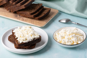 Delicious dark bread topped with fresh cottage cheese served alongside a bowl of creamy cottage cheese