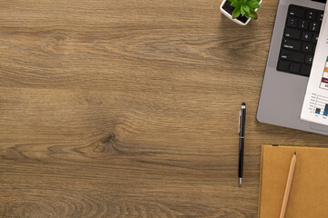 Top view of a wooden office desk with a laptop, financial documents and notebook. A clean and organized workspace for productivity and planning