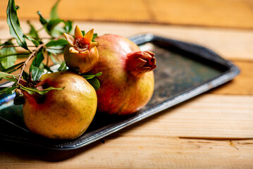 Pomegranates, beautiful freshly picked pomegranates on a wonderful tray on a rustic surface,...