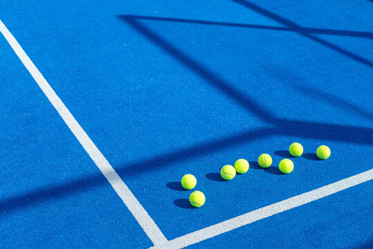 blue paddle tennis court, eight tennis balls near the lines. Racket sport concept background