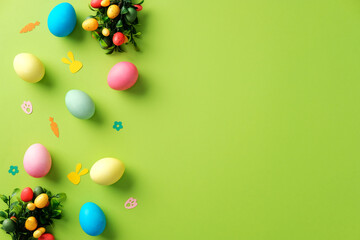 Happy Easter background with colorful Easter eggs and confetti on bright green table.