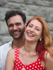 Fototapeta premium portrait of young smiling couple in love outdoors on summer day with house wall in background