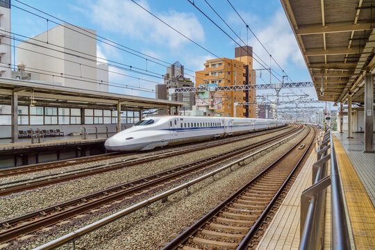 Hamamatsu,Japan - June 27, 2024:  White Shinkansen bullet train passing through Hamamatsu Train Station at high speed.