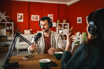 man host interviewer woman guest record podcast at home studio