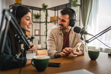 man and woman record together podcast in home studio and use cellphone