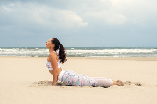 Young Woman Practicing Yoga Beach Pose Meditation Wellness Fitness Exercise Stretching Ocean Seashore Relaxation Healthy Lifestyle Vacation Mindfulness - Powered by Adobe