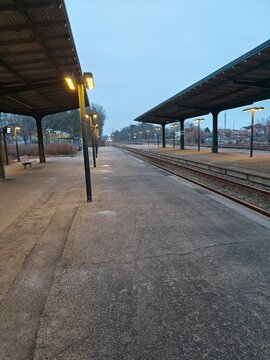 Train station platform during early morning with long tracks, and a quiet, peaceful atmosphere, waiting for the next train. T&oslash;nder railway station.