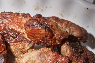 Skewered kebabs and homemade sausages in a white porcelain mold. Close-up.