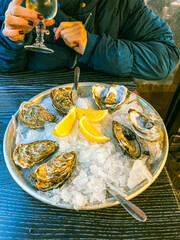 Fresh oysters on ice with lemon and white wine in a restaurant on a wood table