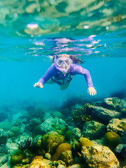 girl snorkeling through a coral reef  in the Caribbean ocean
