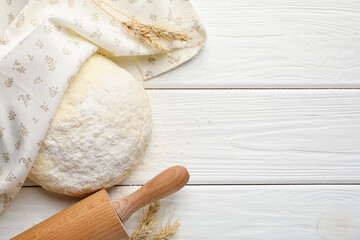 Fresh dough, rolling pin and spikes on white wooden table, flat lay. Space for text