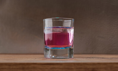 Refreshing pink drink on on wooden surface. The condensation on the glass hints at its refreshing coldness. Selective focus.
