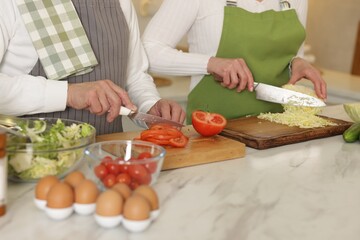 Senior couple cooking together at table in kitchen, closeup