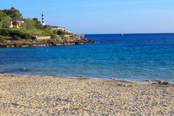Obraz premium Europe, Spain, Balearic Islands, Mallorca. Porto Colom. lighthouse, children play on beach. 2017-04-16