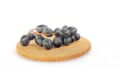 Black grapes still attached to the stem with a black background