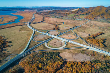 Aerial view of modern highway intersections surrounded by autumn landscape in rural area
