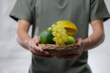 Obraz premium Fresh Organic Fruit Arrangement in Hands with Woven Basket Display