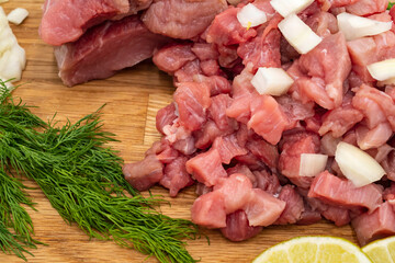 Fresh raw meat with dill, lime and vegetables on wooden background, close-up