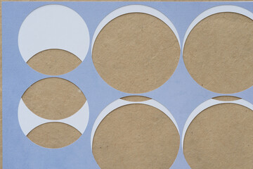 two paper stencils with circle cutouts on brown paper
