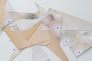 pile of machine-cut paper shapes with grid and radial patterns on blank paper