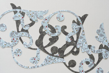 overlapping, machine-cut decorative curved paper flourishes in mostly blue and gray on blank paper
