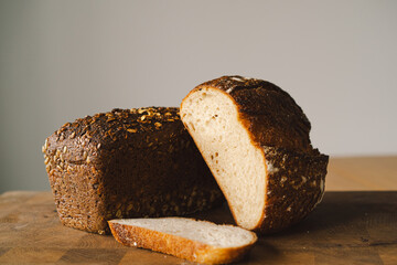 Sourdough bread, freshly baked and still warm, are stacked on a wooden surface. The bread are covered in seeds sesame and sunflower, adding a rustic and flavorful touch.