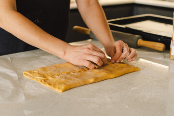 A woman in casual attire prepares dough for baking. She looks pleased and focused, enjoying the baking process in a light-filled kitchen.
