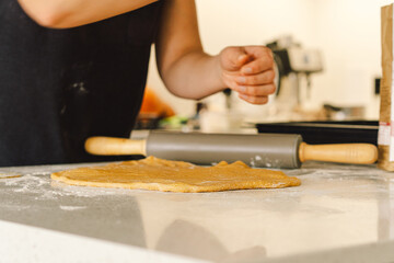 A woman in casual attire prepares dough for baking. She looks pleased and focused, enjoying the baking process in a light-filled kitchen.