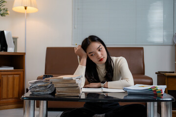Asian female student looking exhausted and overwhelmed by studying for exams at home