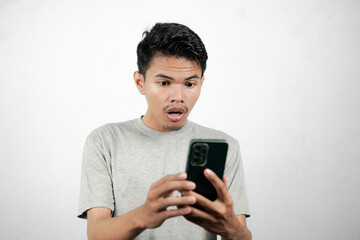 Asian man showing shocked expression while pointing at his smartphone