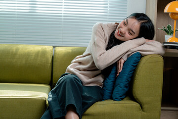 Obraz premium Happy asian woman lying on sofa enjoying weekend at home, relaxing on comfortable couch