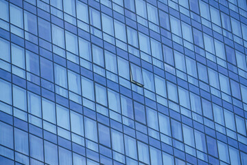 Modern building facade with reflections of sky and missing window