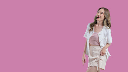 A woman is pointing to the sky with her finger. She is wearing a white jacket and a pink shirt