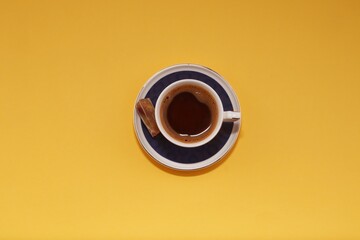 A cup of Turkish coffee with a small Turkish delight placed on solid yellow background, eid mubarek