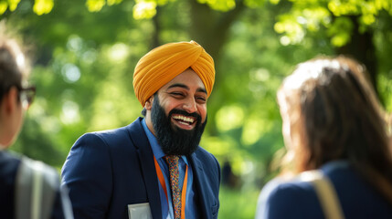 Naklejka premium A cheerful man in a traditional turban engages with two women in a sunlit park, surrounded by lush greenery, capturing a moment of joyful interaction