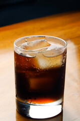 Refreshing Cola with Ice on Wooden Table

