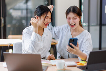 Two happy business asian women coworking with a laptop in a desktop at office
