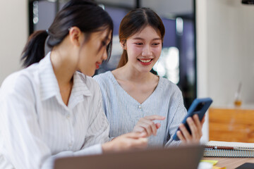 Obraz premium Two happy business asian women coworking with a laptop in a desktop at office 