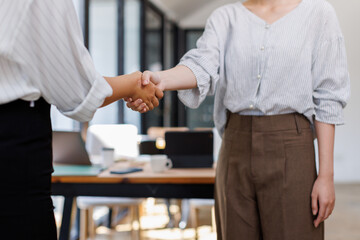 Fototapeta premium Cheerful asian businesswomen shaking hands in meeting room 