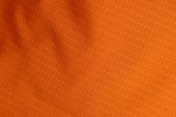 Orange fleece fabric is part of a garment, part of a raincoat made of beige material with a short...